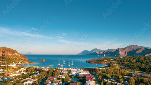 Fototapeta Naklejka Na Ścianę i Meble -  Aerial view photo from flying drone of The black sand beach with yachts in small haven in Porto di Ponente, in Vulcano, Italy on a summer at beautiful day with blue sky (series)