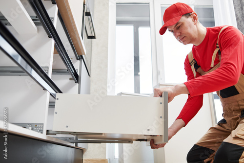 kitchen installation. Worker assembling furniture