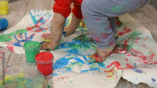Adorable cute caucasian little blond siblings children enjoy having fun together with mother painting brush and palm at home indoors . Cheerful happy kids smiling drawing masterpiece art picture