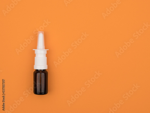 A bottle of nose drops on orange background close-up.