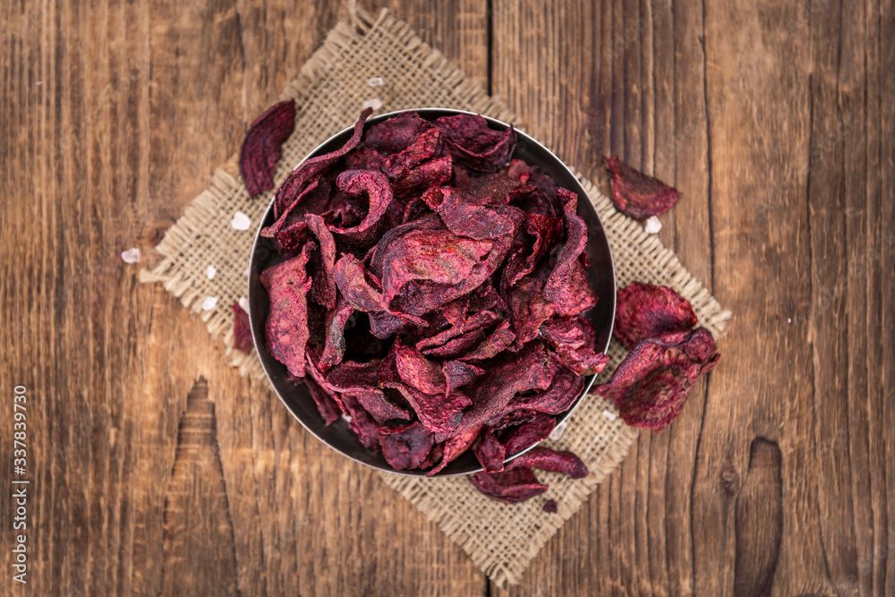 Some Beetroot Chips on a vintage wooden table (selective focus; close-up shot)