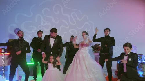 happy bridegroom and bride dancing with guests at the wedding party ,multi-colored balls on the floor,room with decorated with colorful neon lights,