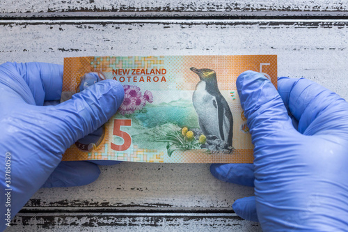 New Zealand five Dollar banknote kept in rubber gloves. The concept of economy and financial threats during the Coronavirus pandemic photo