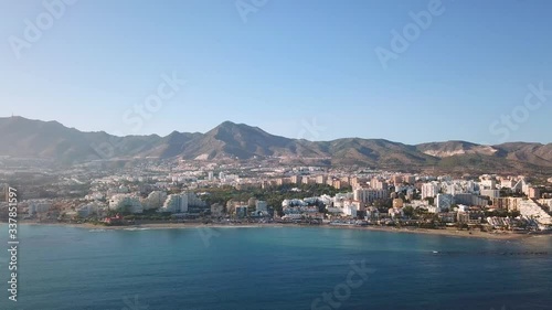Aerial View of Benalmadena, Costa del Sol, Malaga, Spain. Panoramic view over the city and mountains in the background at the beginning of sunset, with soft warm light over the buildings photo