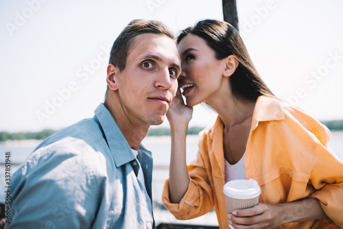 Content woman telling gossip mate on seafront