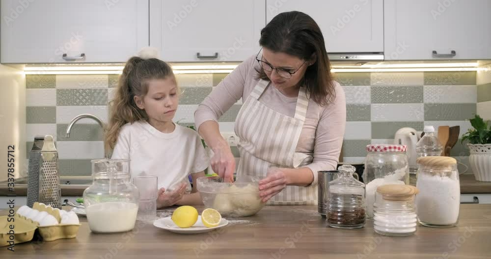 Mothers day, mother and daughter child together at home kitchen preparing cookies, kneading dough in bowl Mothers day, mother and daughter child together at home kitchen preparing cookies, kneading dough in bowl