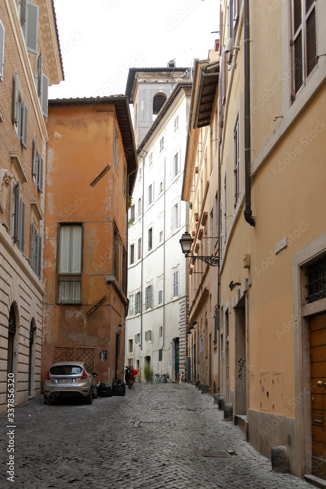 A narrow alley in the center of Rome. Medieval buildings. There's no one on the street.