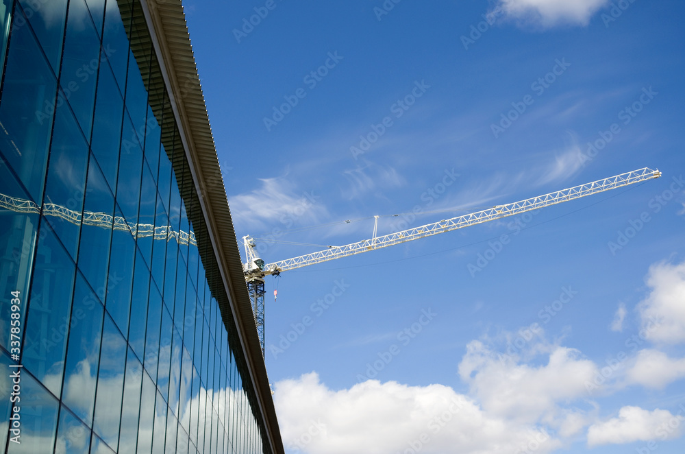 Fototapeta premium Construction Crane Over a Glass Building with Blue Sky