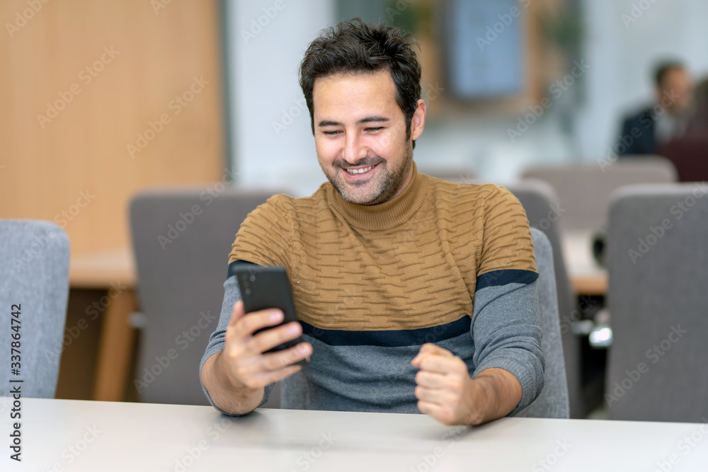 A young man watching a football game with a smartphone in great excitement A young man watching a football game with a smartphone in great excitement