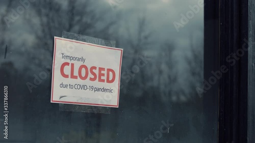 FIXED view of a Temporary closed due COVID-19 pandemic sign hanging on a window. Coronavirus pandemic, small business shutdown photo