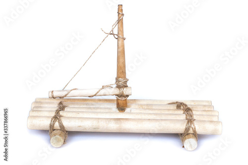 Toy wooden raft made of natural logs and ropes with a mast. Isolated on white background.