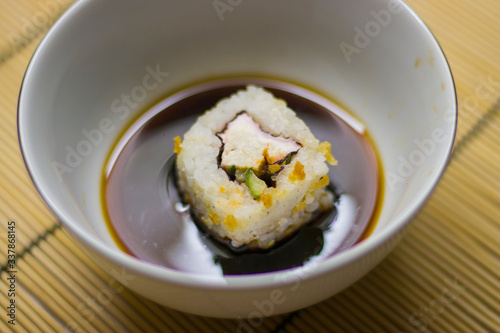 japanese food roll with black chopsticks and soy sauce in a white plate on the table
