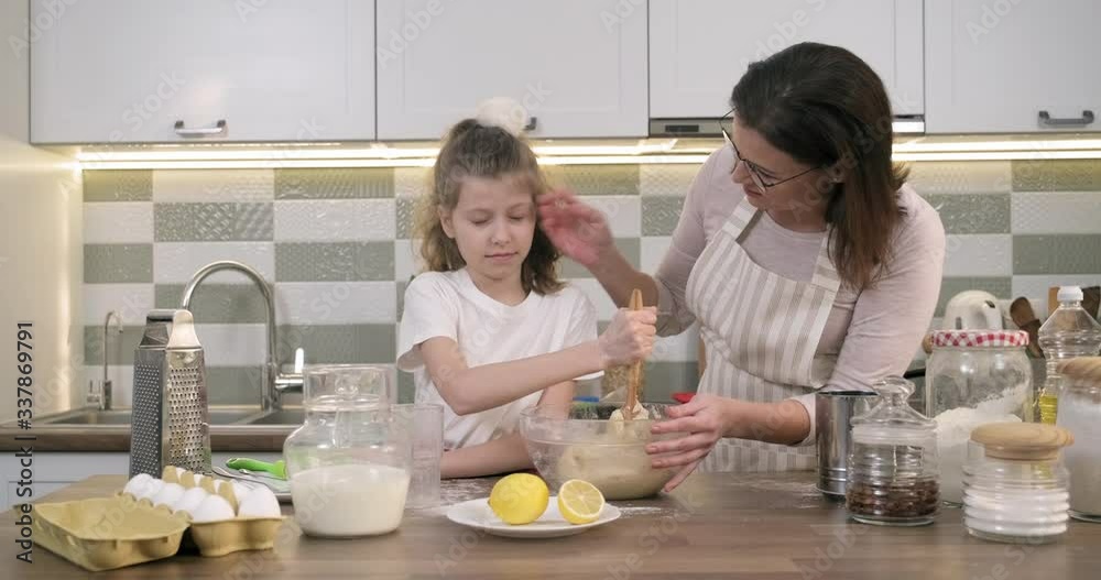 Mothers day, mother and daughter child together at home kitchen preparing cookies, kneading dough in bowl Mothers day, mother and daughter child together at home kitchen preparing cookies, kneading dough in bowl