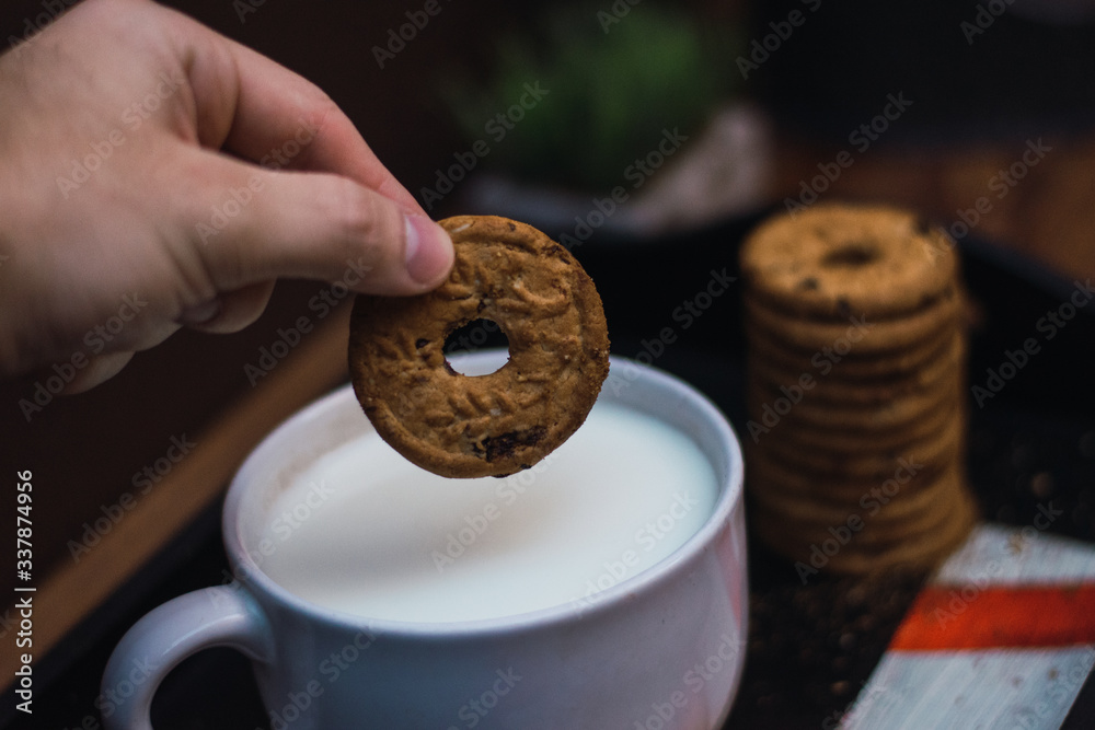 Fototapeta premium mano metiendo una galleta en un tazón de leche