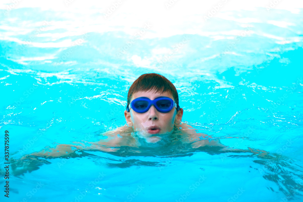 Naklejka premium Teen boy swims in the pool. Healthy lifestyle concept. Close-up.