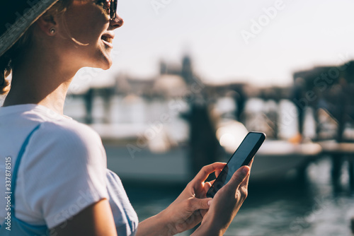 Happy young charming woman with smartphone on channel pier