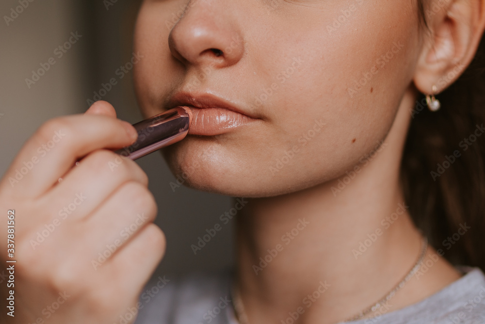 Portrait of a young caucasian girl putting lipstick on her mouth