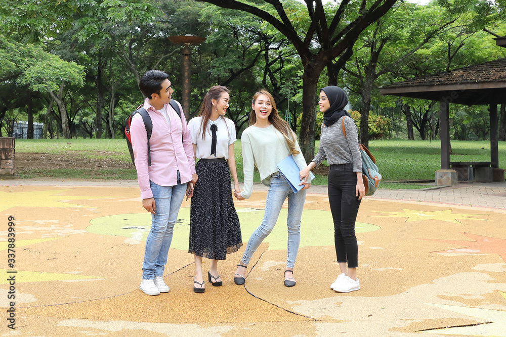 Young asian malay chinese man woman outdoor park walk stand study talk discuss point laptop file book backpack Young asian malay chinese man woman outdoor park walk stand study talk discuss point laptop file book backpack