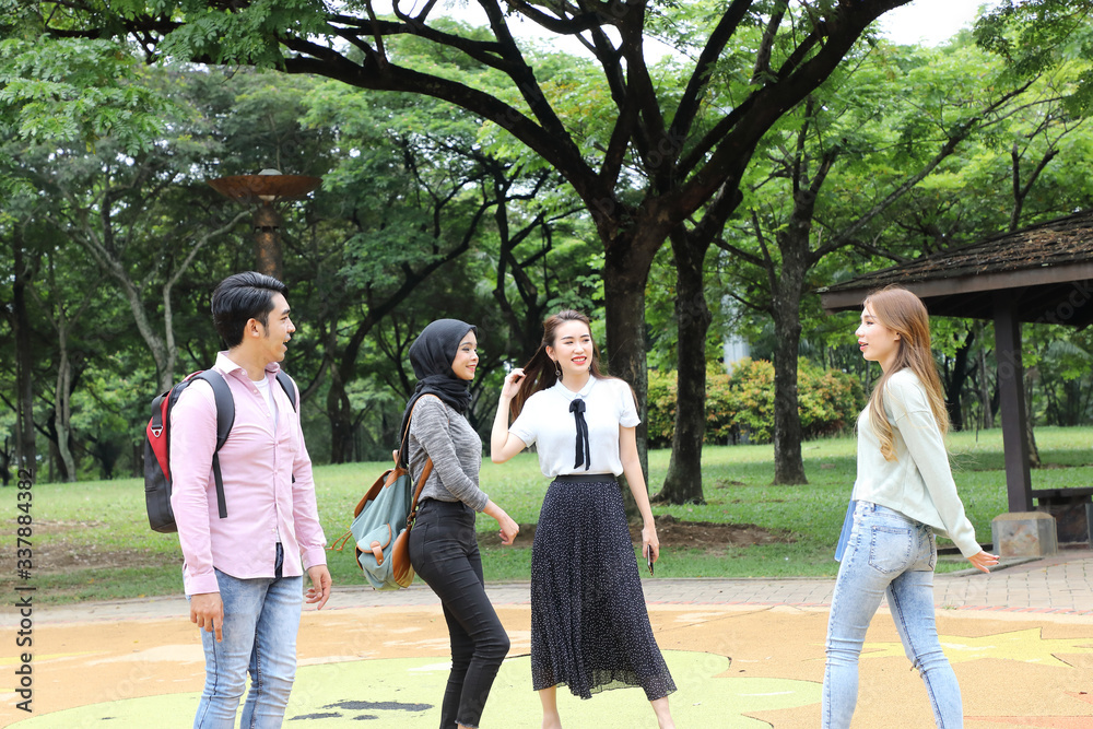 Young asian malay chinese man woman outdoor park walk stand study talk discuss point laptop file book backpack mingle fun Young asian malay chinese man woman outdoor park walk stand study talk discuss point laptop file book backpack mingle fun