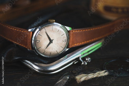 Vintage watch with brown leather strap, lying between different vintage stuff.