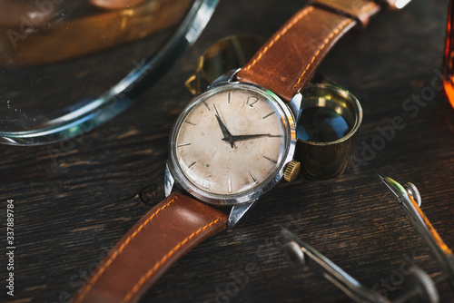 Vintage watch with brown leather strap, lying between different vintage stuff.