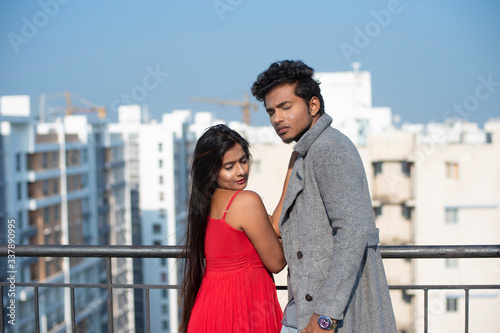 An young Indian brunette couple in western dress enjoying themselves on the rooftop in urban background in home quarantine. Indian lifestyle.