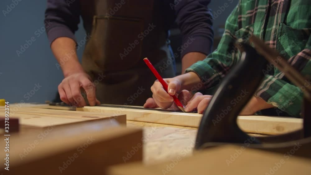 Boy with pencil makes serifs on a wooden board. Garage workshop Boy with pencil makes serifs on a wooden board. Garage workshop