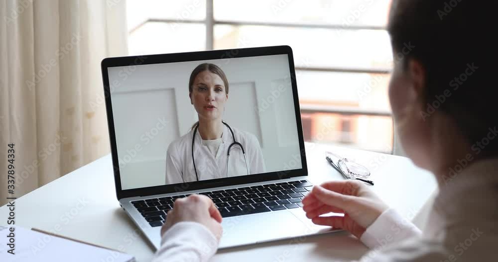Telemedicine videoconference concept. Friendly female doctor consulting woman client patient by video call remote healthcare web cam app chat on laptop. Over shoulder closeup computer screen view Telemedicine videoconference concept. Friendly female doctor consulting woman client patient by video call remote healthcare web cam app chat on laptop. Over shoulder closeup computer screen view
