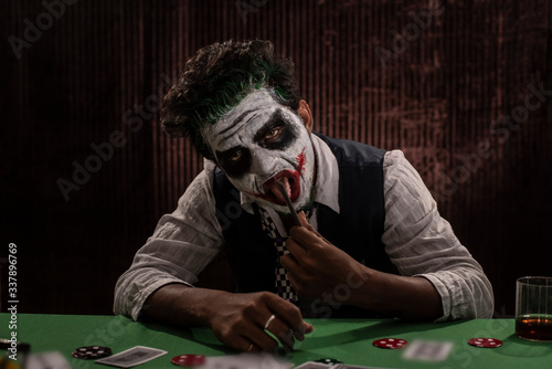 Portrait of an Indian man in Halloween costume showing scary facial expression in front of a casino poker table. Cosplay photography. photo