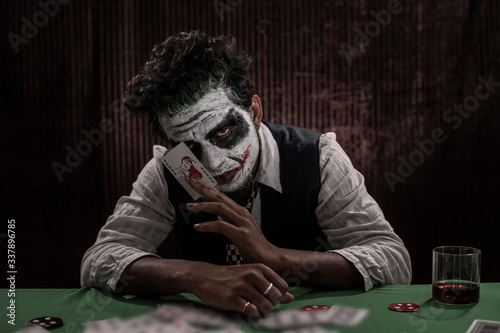 Portrait of an Indian man in Halloween costume showing scary facial expression in front of a casino poker table. Cosplay photography. photo