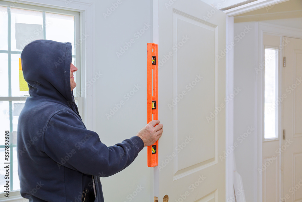 Worker checks the leveling new door of install in the interior room Worker checks the leveling new door of install in the interior room