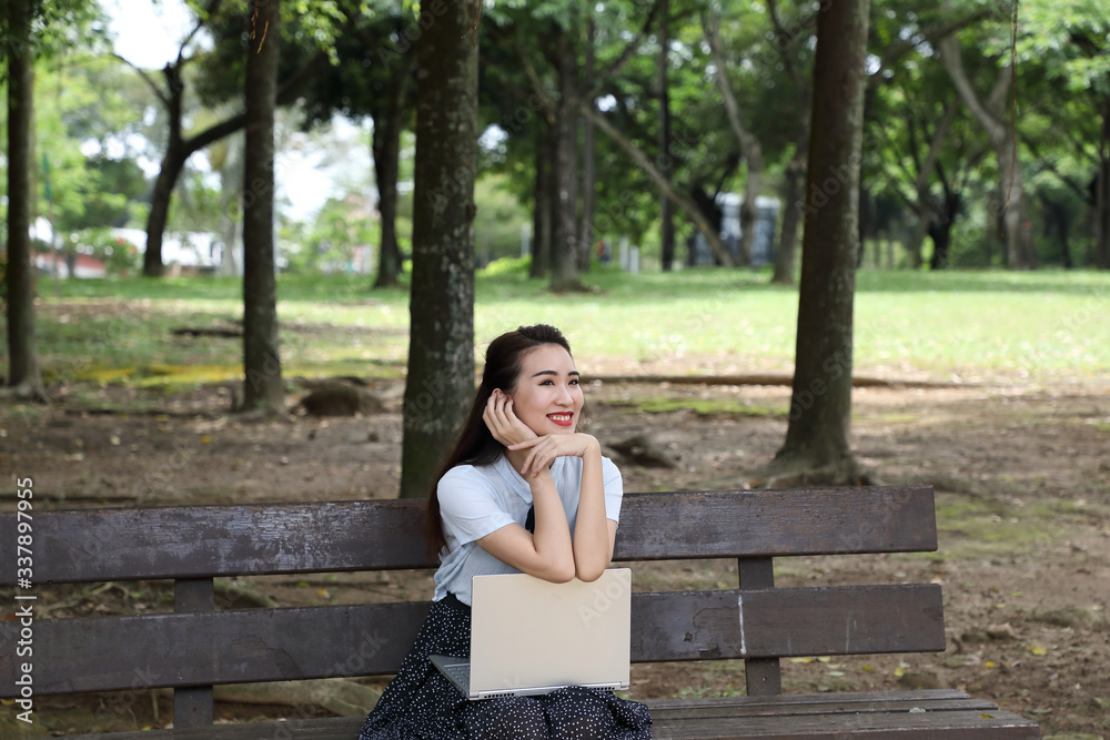 Obraz premium Young asian chinese woman outdoor on park bench use laptop computer think read look happy wonder smile look front retro hand on cheek