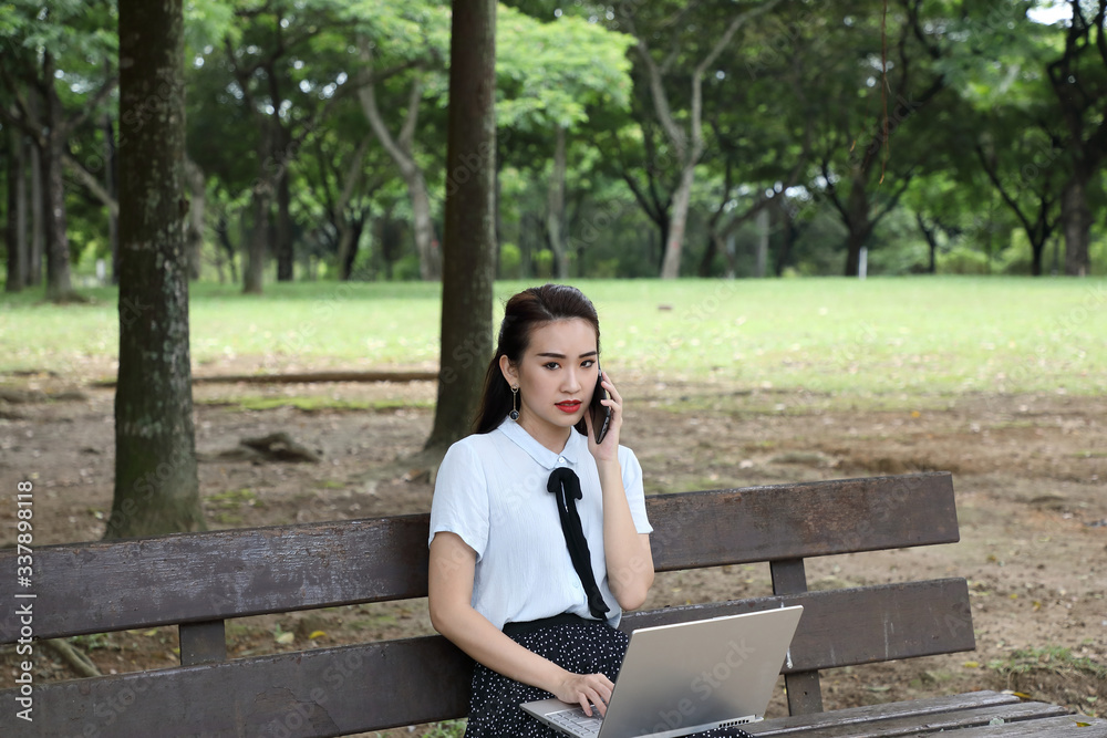 Young asian chinese woman outdoor on park bench use laptop computer think read look happy wonder serous front talk on phone