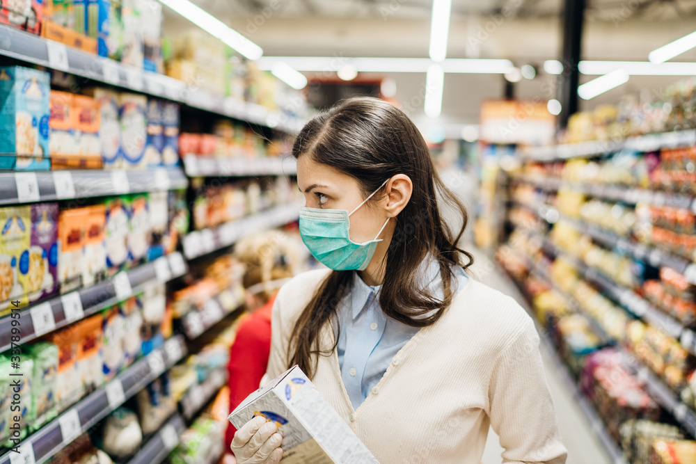 Shopper with mask safely shopping for groceries due to coronavirus pandemic in stocked grocery store.COVID-19 food buying.Non perishable food.Full grain carbs.Rice shortage.Lockdown preparation