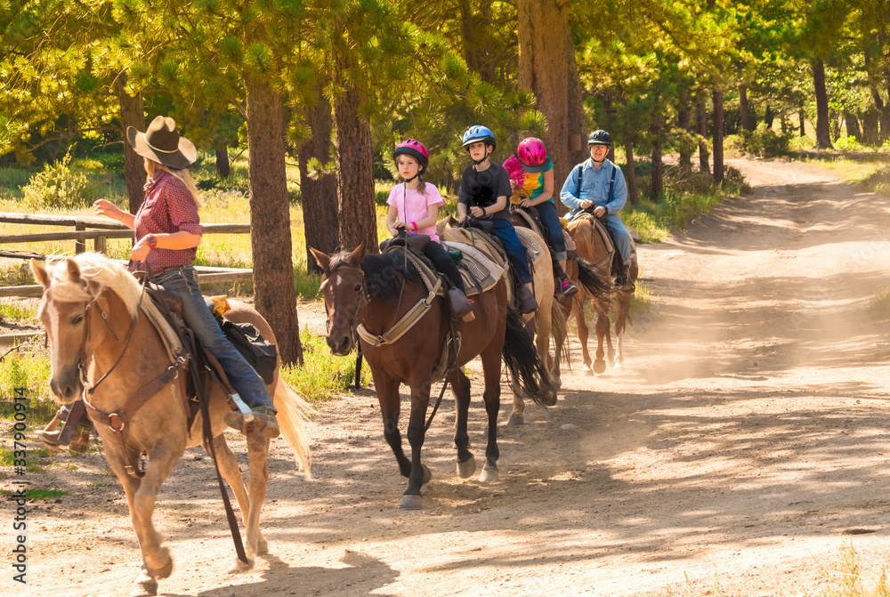 Family taking a horseback riding lesson in the woods in the Rocky Mountains, Colorado, USA, in summer Family taking a horseback riding lesson in the woods in the Rocky Mountains, Colorado, USA, in summer