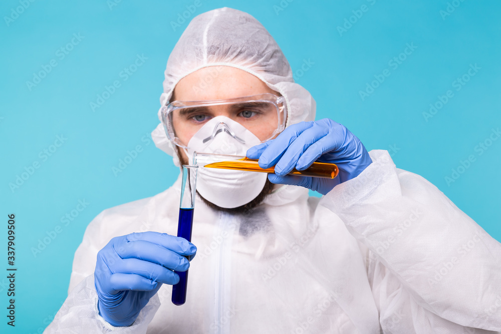 Covid-19, Vaccine development, pandemic, outbreak and coronavirus concept - Man scientist dressed personal protective equipment holding a test tube and does a chemical experiment.