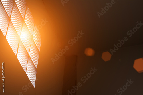 Bright sunlight streaming into a living room interior with a parquet floor and couch through a large window with lens flare 