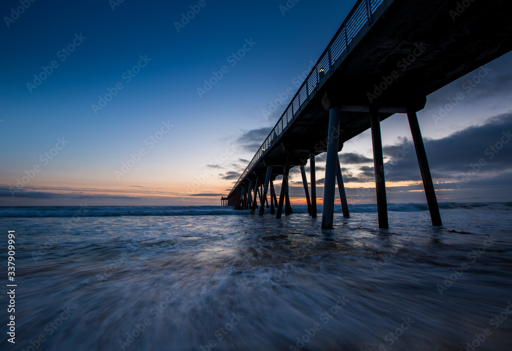 Long exposure of waves rushing in underneath the Hermosa Beach Pier just after sunset in Hermosa Beach, California.