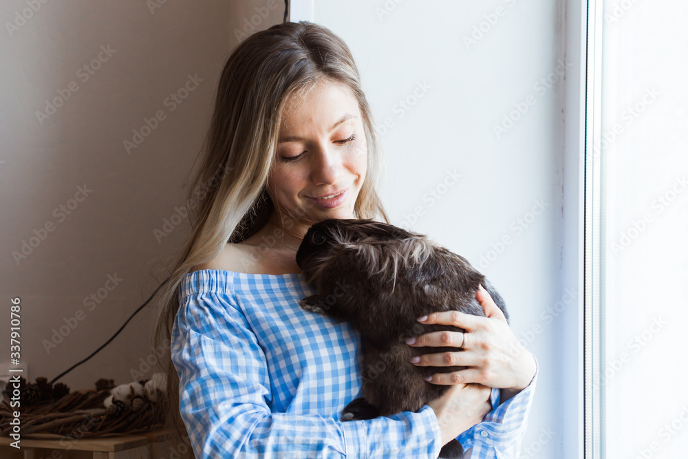 Fototapeta premium Pet and Easter concept - Happy girl hugging brown rabbit at home.
