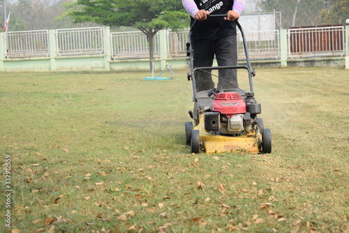Male workers mowing fields with small motor vehicles