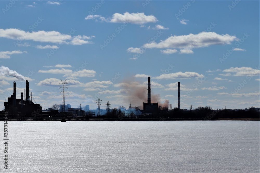 A frozen pond on the banks of which are factory buildings and pipes.