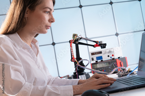 Woman student with industrial robot arm in laboratory