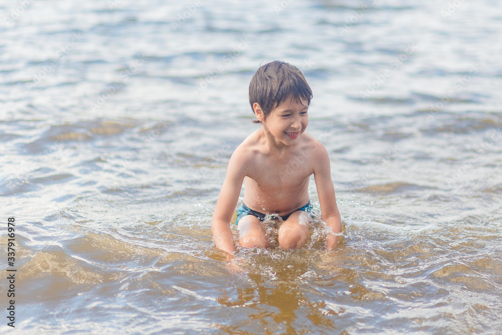boy in blue swimming trunks having fun in the lake in summer boy in blue swimming trunks having fun in the lake in summer