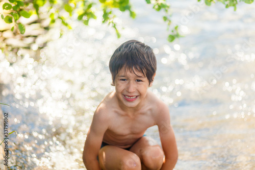 boy in blue swimming trunks having fun in the lake in summer