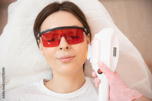 Master carries out removal of unwanted hair laser on face young woman. Health and beauty concept