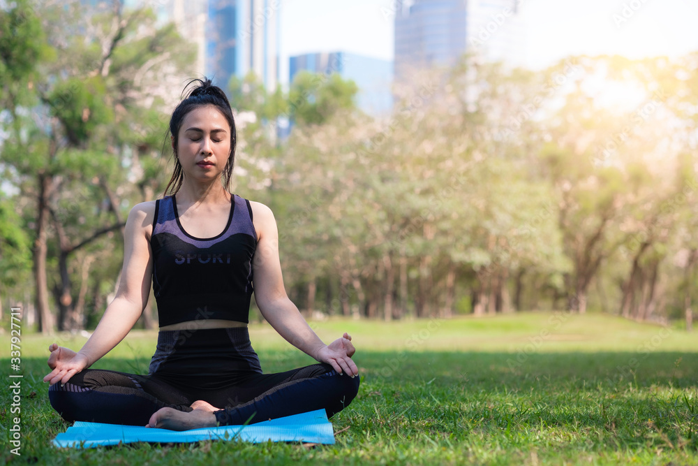 Asian woman wearing a black sports bra is exercising by yoga in a public park. Urban health care concept. Asian woman wearing a black sports bra is exercising by yoga in a public park. Urban health care concept.