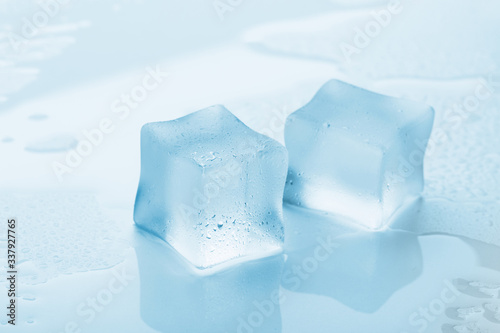 several melted ice cubes with drops on a light background with blue tinting © Nana_studio
