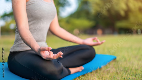 Asian woman meditating and sit in the lotus pose at park, Healthy and Yoga Concept,Mind-body improvements concept, Selective focus, Copy space.