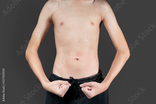 Boy is very thin Try to contract the stomach That does not have fat around the waist To see the wrinkles of the muscles. photo