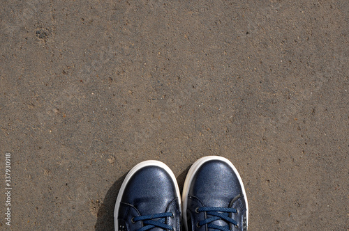 feet in blue sneakers standing on the street-selfie feet from a personal perspective - asphalt background with a copy of the space